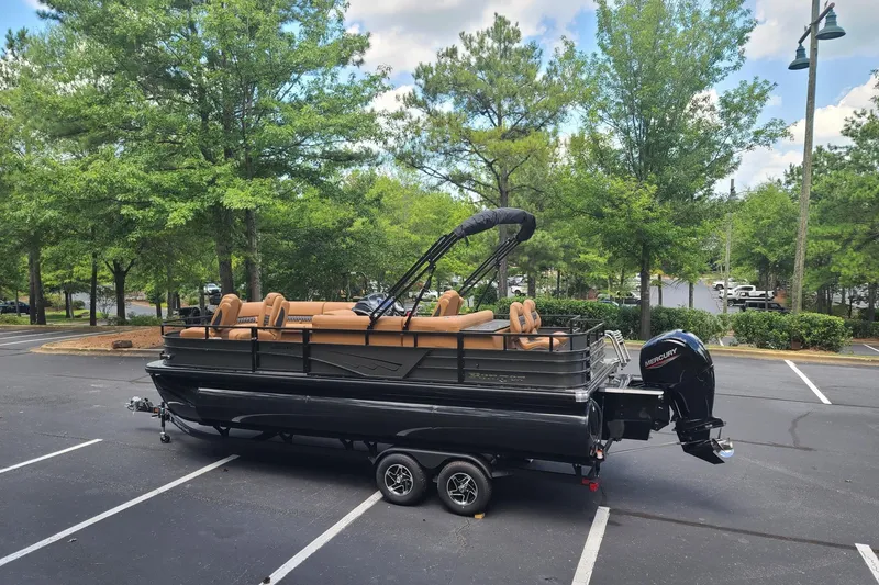 Slide: The Image of 2026 Ranger 223FC pontoon boat on trailer in parking lot, surrounded by trees. - 2