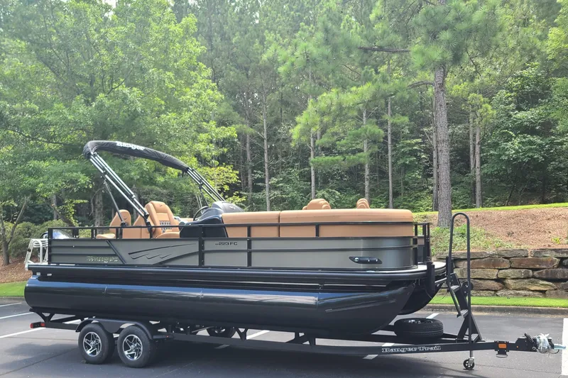 Slide: The Image of 2026 Ranger 223FC pontoon boat on trailer, parked in a wooded area. - 6