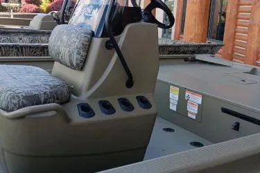 Slide: The Image of 2026 Tracker Grizzly 1860 CC boat interior with steering console and cushioned seating. - 9