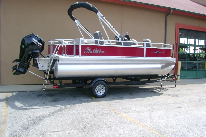 Slide: The Image of 2026 Sun Tracker Bass Buggy 18 DLX pontoon boat on trailer, parked outdoors. - 3