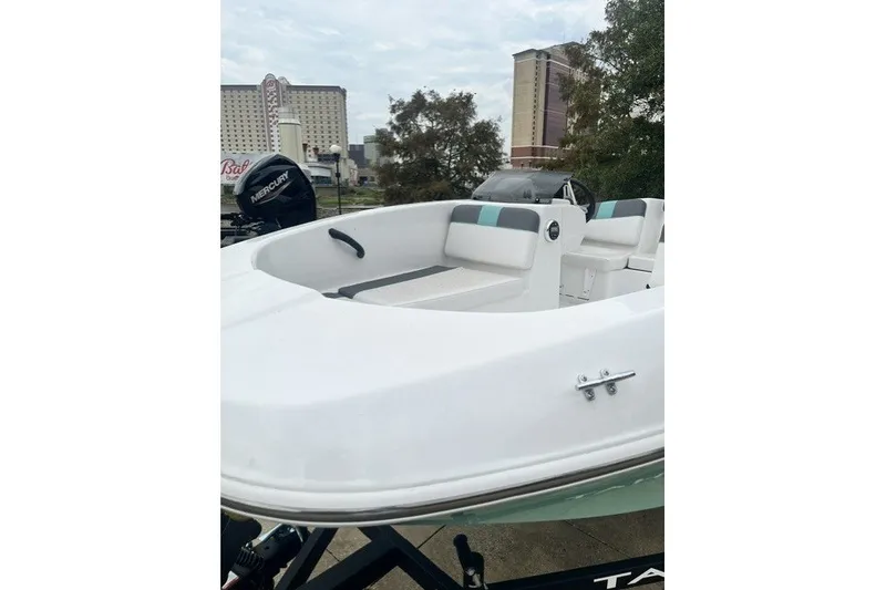 Slide: The Image of 2026 Tahoe T16 boat with Mercury engine, docked near urban buildings. - 2