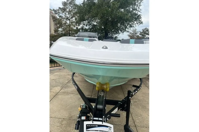 Slide: The Image of 2026 Tahoe T16 boat on trailer, parked outdoors with trees in background. - 9