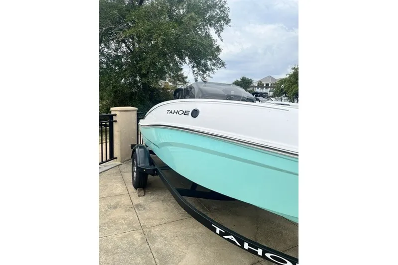 The Image of 2026 Tahoe T16 boat on trailer, parked outdoors near trees and buildings. - 0