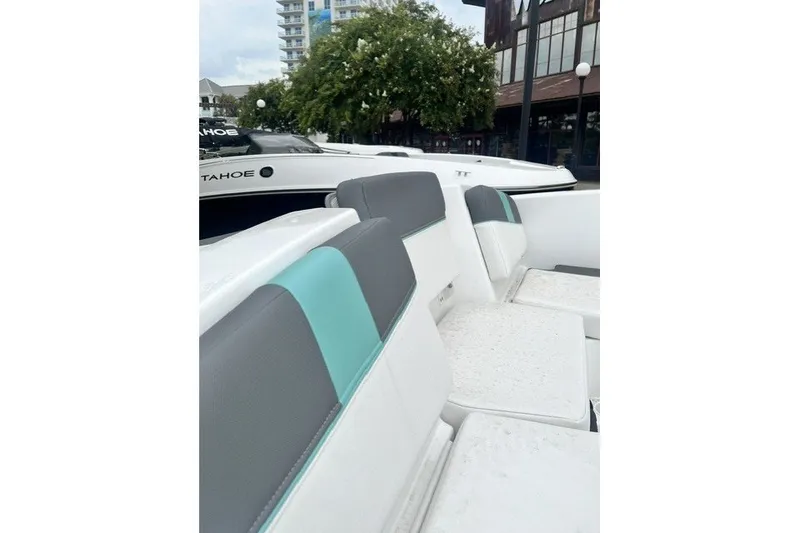 Slide: The Image of 2026 Tahoe T16 boat interior with gray and teal seating, docked near buildings. - 11