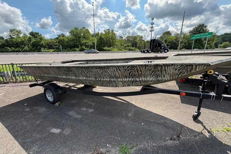 The Image of 2026 Tracker Grizzly 1648 Utility boat on trailer, parked outdoors under a cloudy sky. - 0