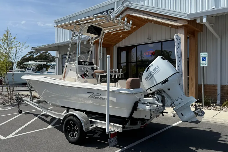 Slide: The Image of 2022 Pioneer 180 Sportfish boat with Suzuki engine parked outside a building. - 9