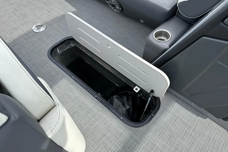 Slide: The Image of 2024 Veranda VP25RCT boat storage compartment with open hatch, gray interior, and cup holder. - 14