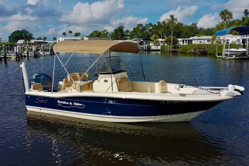 The Image of 2024 Scout 195 Sportfish boat on calm water with canopy and Yamaha motor. - 0