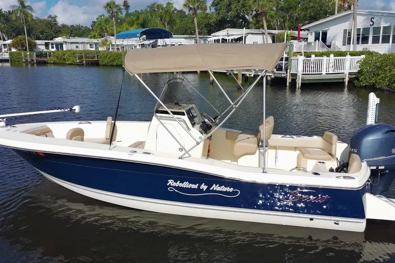 Slide: The Image of 2024 Scout 195 Sportfish boat with canopy on a calm river. - 12