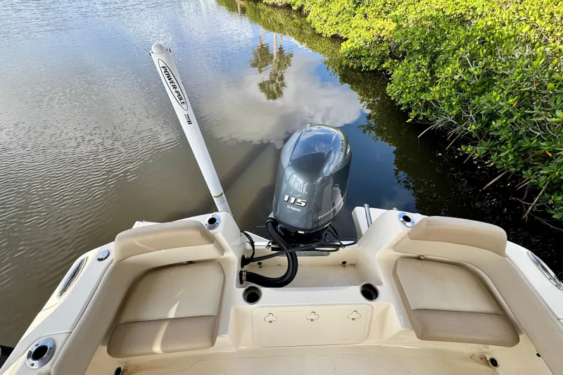 Slide: The Image of 2024 Scout 195 Sportfish boat with Yamaha 115 engine, docked near lush greenery. - 13