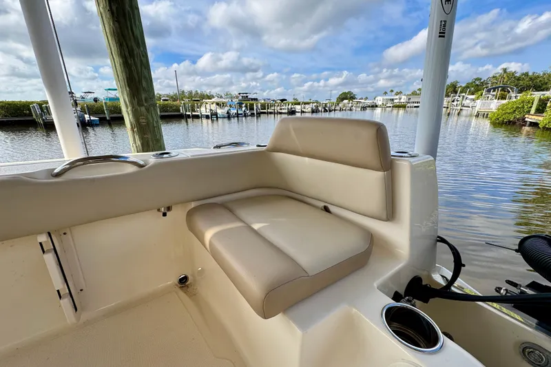 Slide: The Image of 2024 Scout 195 Sportfish boat interior with beige seating, docked by a serene waterfront. - 15