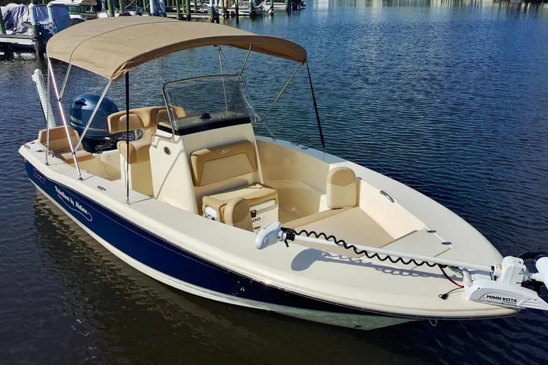 Slide: The Image of 2024 Scout 195 Sportfish boat with canopy on calm water. - 2