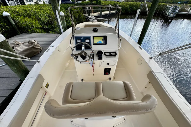 Slide: The Image of 2024 Scout 195 Sportfish boat interior with steering console and seating, docked by the water. - 21