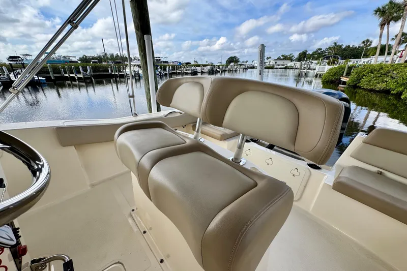 Slide: The Image of 2024 Scout 195 Sportfish boat interior with beige seating, dockside view. - 22