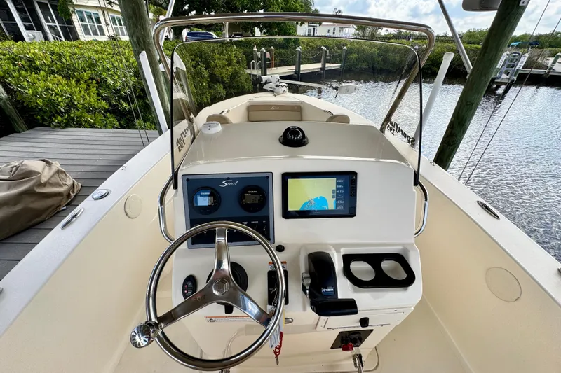 Slide: The Image of 2024 Scout 195 Sportfish boat dashboard with steering wheel and navigation display. - 25