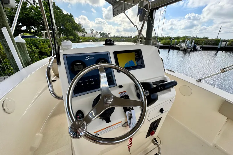 Slide: The Image of 2024 Scout 195 Sportfish boat helm with steering wheel and navigation display. - 26