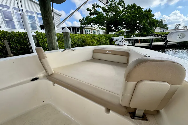 Slide: The Image of 2024 Scout 195 Sportfish boat interior with beige seating, docked near waterfront homes. - 34