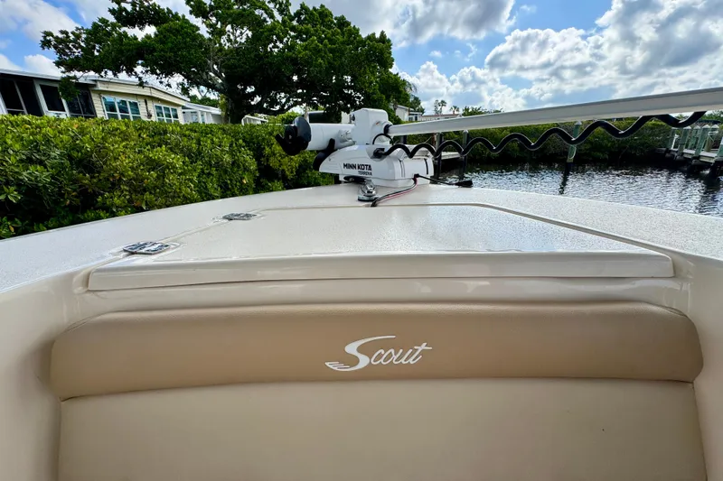 Slide: The Image of 2024 Scout 195 Sportfish boat with Minn Kota motor, docked near lush greenery. - 36