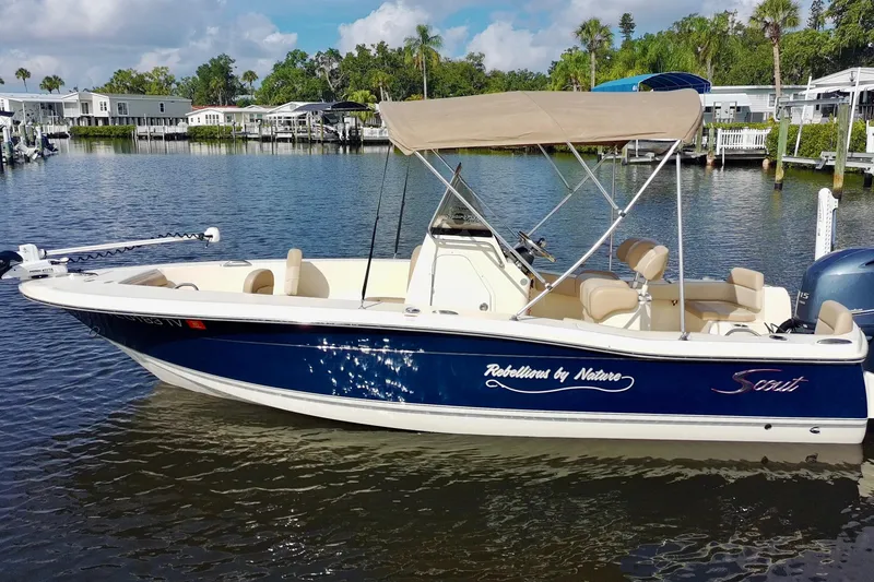 Slide: The Image of 2024 Scout 195 Sportfish boat with canopy on a calm waterfront. - 8