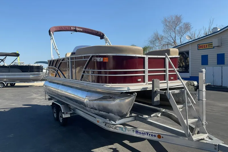 Slide: The Image of 2021 Sylvan Mirage Fish 820 Party Fish pontoon boat on trailer, parked near a deli. - 3
