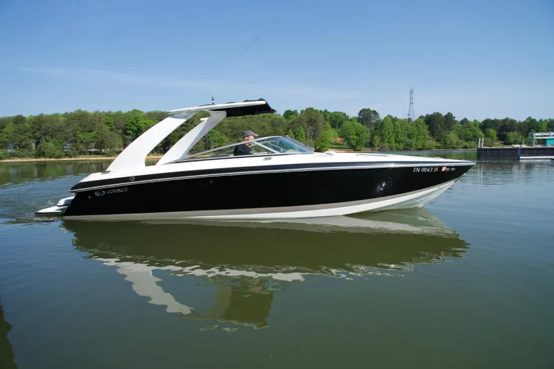 The Image of 2005 Cobalt 262 boat cruising on a calm lake with lush green shoreline. - 1
