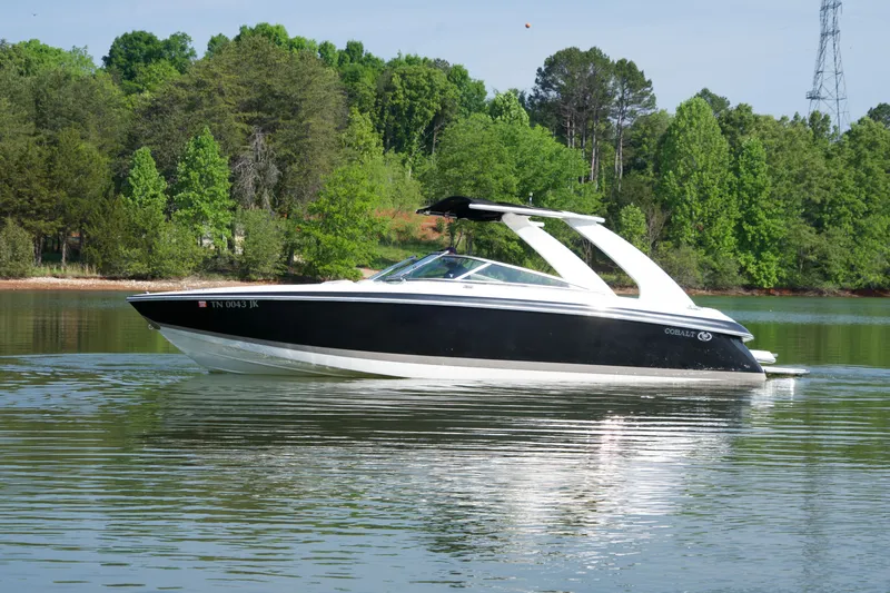 Slide: The Image of 2005 Cobalt 262 boat cruising on a serene lake with lush green trees. - 15