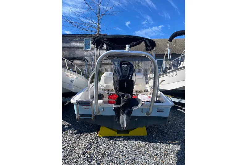 Slide: The Image of 2018 Boston Whaler 150 Super Sport boat with outboard motor, parked on gravel. - 10