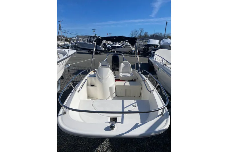 Slide: The Image of 2018 Boston Whaler 150 Super Sport boat in a marina, clear sky background. - 2