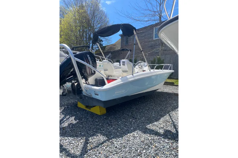 Slide: The Image of 2018 Boston Whaler 150 Super Sport boat on gravel, with Mercury engine and canopy. - 3