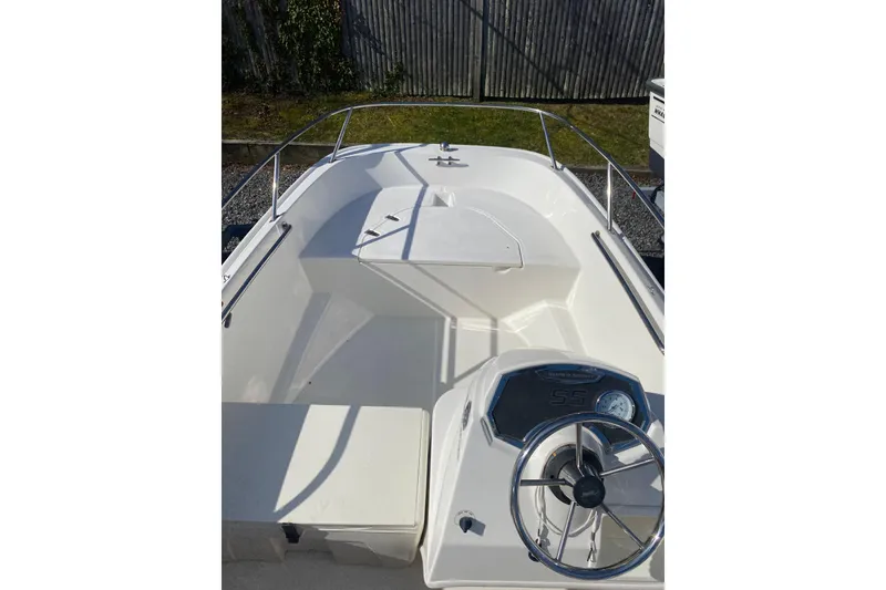Slide: The Image of 2018 Boston Whaler 150 Super Sport boat interior with steering wheel and seating. - 4