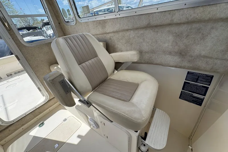 Slide: The Image of Captain's chair inside 2016 Defiance Admiral 270 EX boat, featuring beige upholstery and armrests. - 18