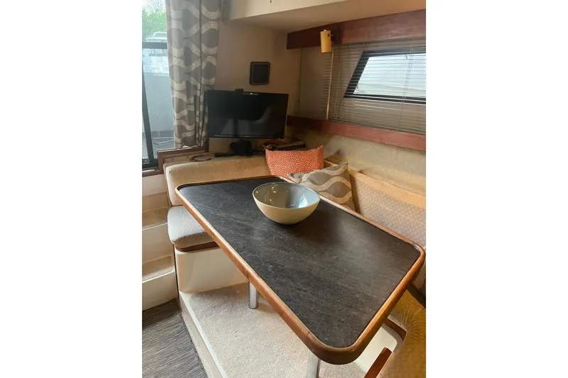 Slide: The Image of Interior of 1986 Carver 3297 Mariner with cozy seating and table setup. - 7