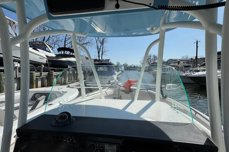 Slide: The Image of 2022 Sailfish 242 CC boat interior view at marina, showcasing helm and windshield. - 14