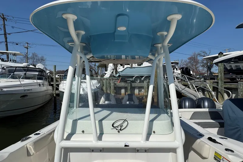 Slide: The Image of 2022 Sailfish 242 CC boat with blue T-top, docked among other boats. - 21