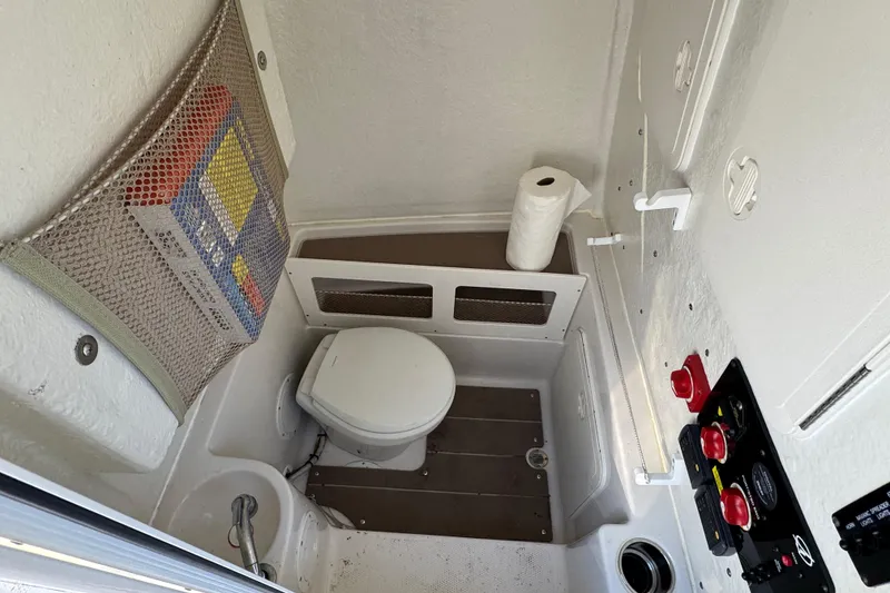 Slide: The Image of Interior of 2022 Sailfish 242 CC boat bathroom with toilet and control panel. - 25