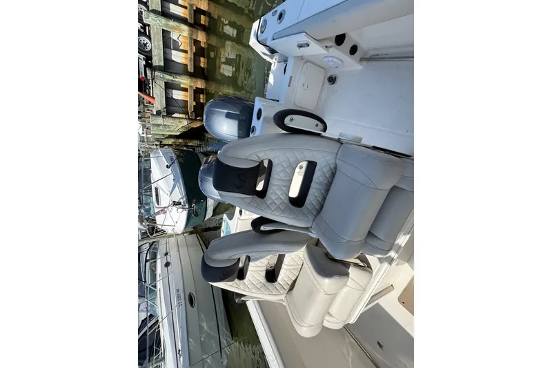 Slide: The Image of 2022 Sailfish 242 CC boat interior with luxurious seating at a marina. - 26