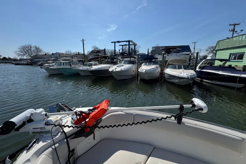 Slide: The Image of 2022 Sailfish 242 CC boat docked with other boats in a marina under clear skies. - 29