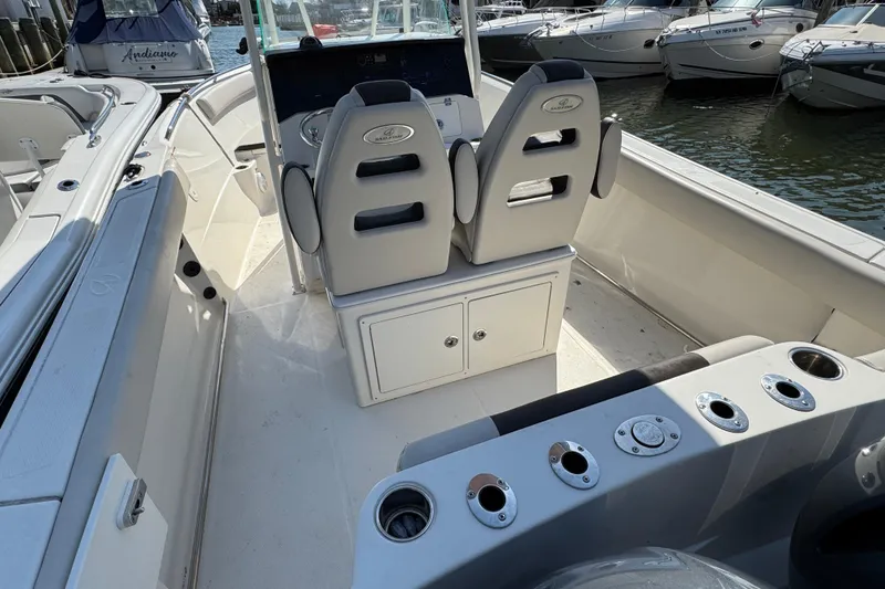 Slide: The Image of 2022 Sailfish 242 CC boat interior with seating and storage, docked among other boats. - 4