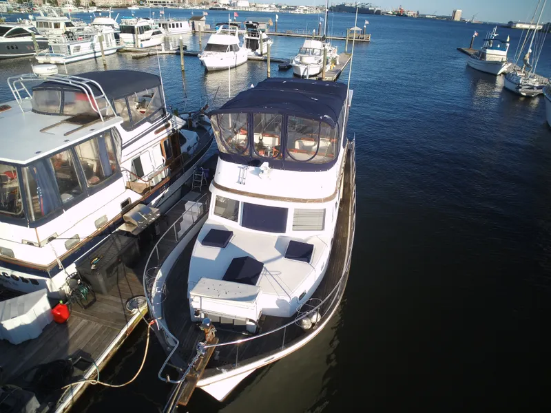 The Image of A 1981 Marine Trader 44 Double Cabin docked in a marina. It features a spacious deck and blue canopy. - 0