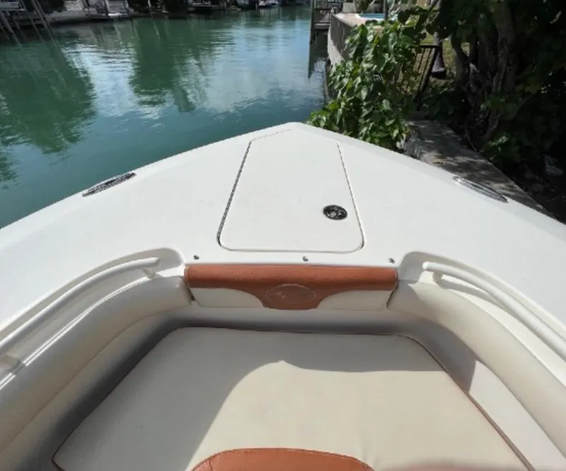 Slide: The Image of Bow view of 2013 Scout 275 LXF boat docked by lush greenery. - 12