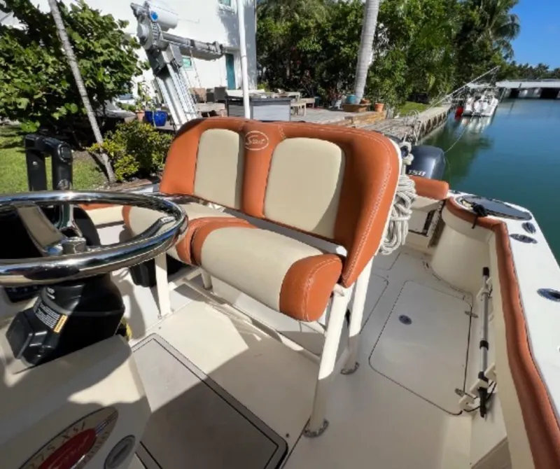 Slide: The Image of 2013 Scout 275 LXF boat interior with tan and orange seating by a canal. - 5