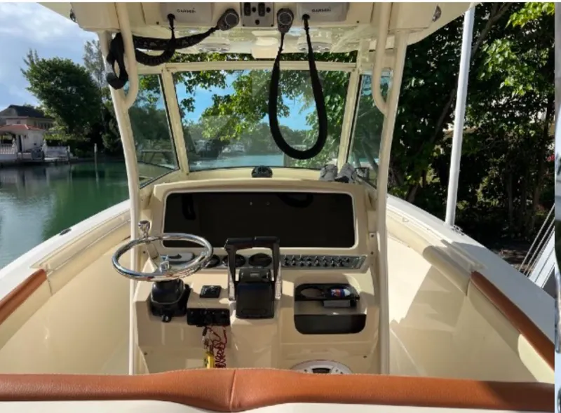 Slide: The Image of 2013 Scout 275 LXF boat cockpit with steering wheel and controls, docked by a scenic waterway. - 7