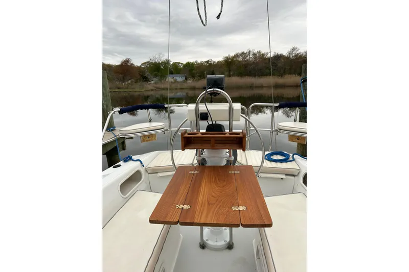 Slide: The Image of Cockpit of a 1994 Catalina 270 sailboat with wooden table and serene water view. - 10