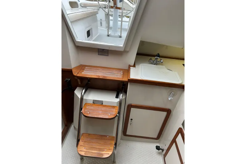 Slide: The Image of Interior of a 1994 Catalina 270 sailboat featuring wooden steps and a compact sink area. - 11