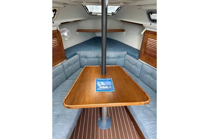 Slide: The Image of Cozy interior of a 1994 Catalina 270 sailboat with a wooden table and cushioned seating. - 12