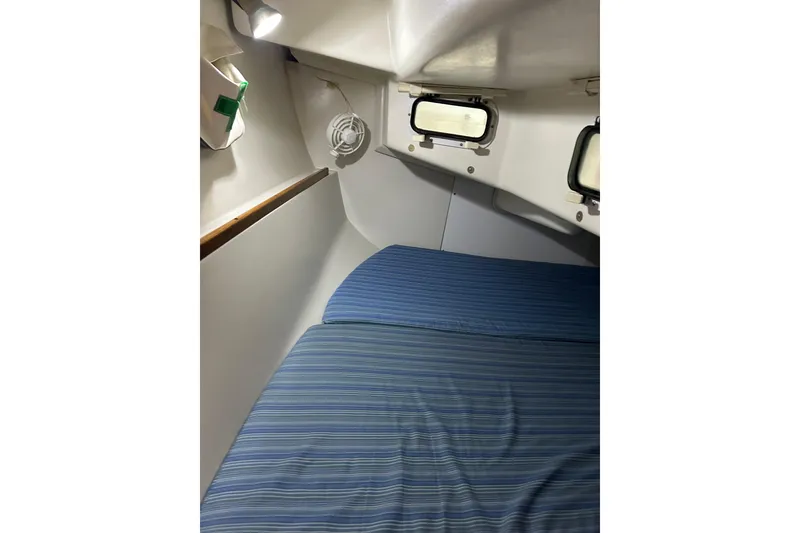 Slide: The Image of Cozy cabin interior of a 1994 Catalina 270 sailboat with striped bedding and portholes. - 15