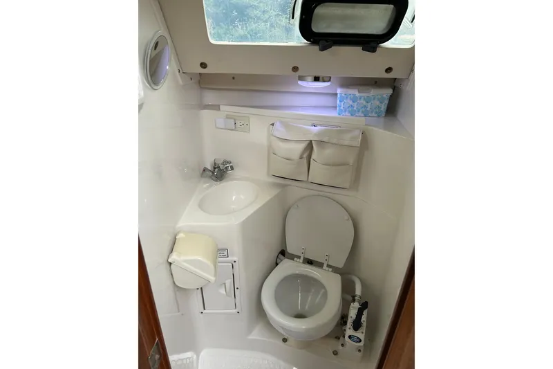 Slide: The Image of Compact bathroom in a 1994 Catalina 270 sailboat, featuring a toilet, sink, and storage. - 18