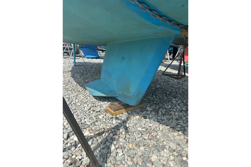 Slide: The Image of 1994 Catalina 270 sailboat keel on gravel, supported by wooden blocks. - 3