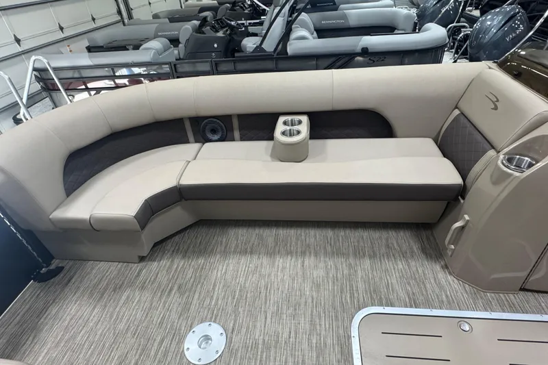 Slide: The Image of 2024 Bennington 24 L Swingback pontoon boat interior with beige seating and cup holders. - 13