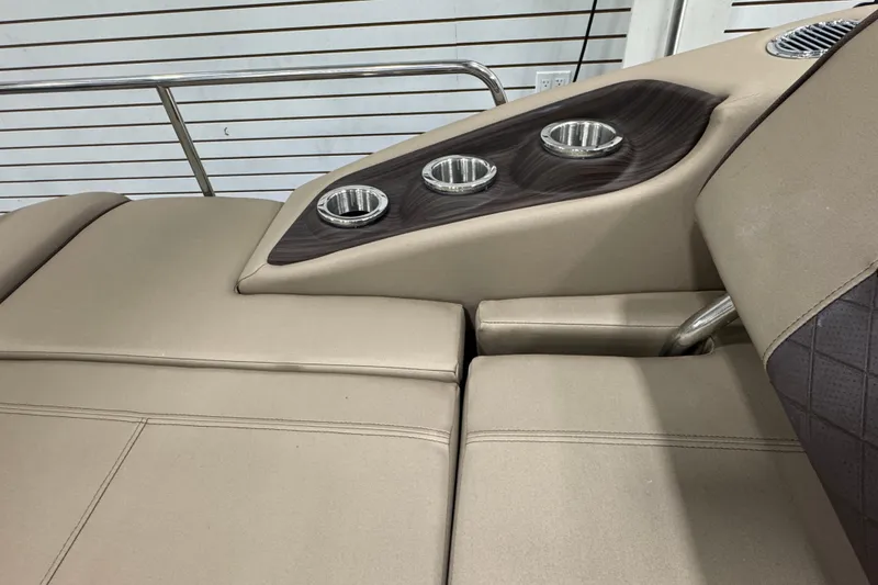 Slide: The Image of 2024 Bennington 24 L Swingback boat interior with cup holders and beige seating. - 21